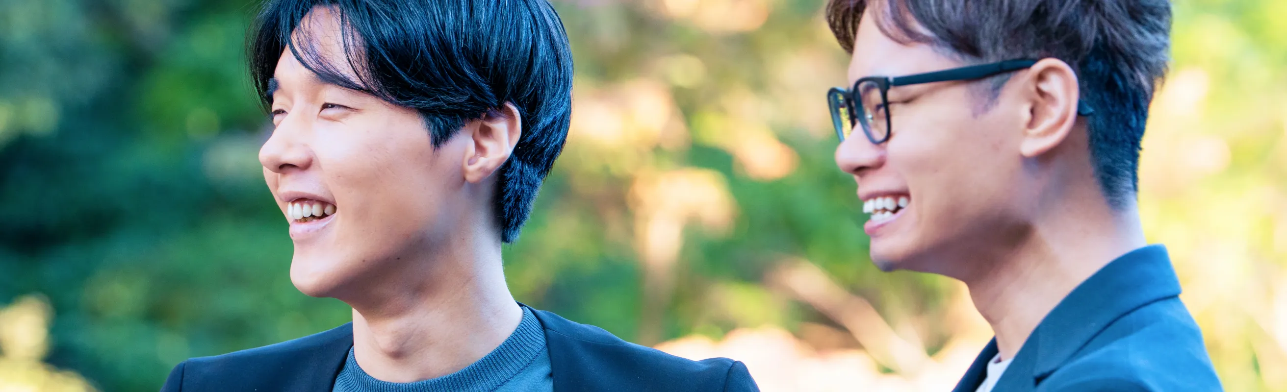 左側を向いている笑顔の2人の男性