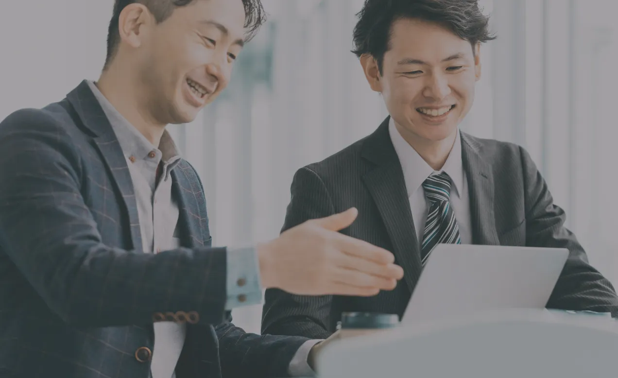 パソコン画面を見ながら打ち合わせをする2人の男性