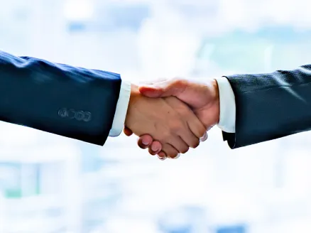 スーツの職員が握手をしている様子の手元拡大